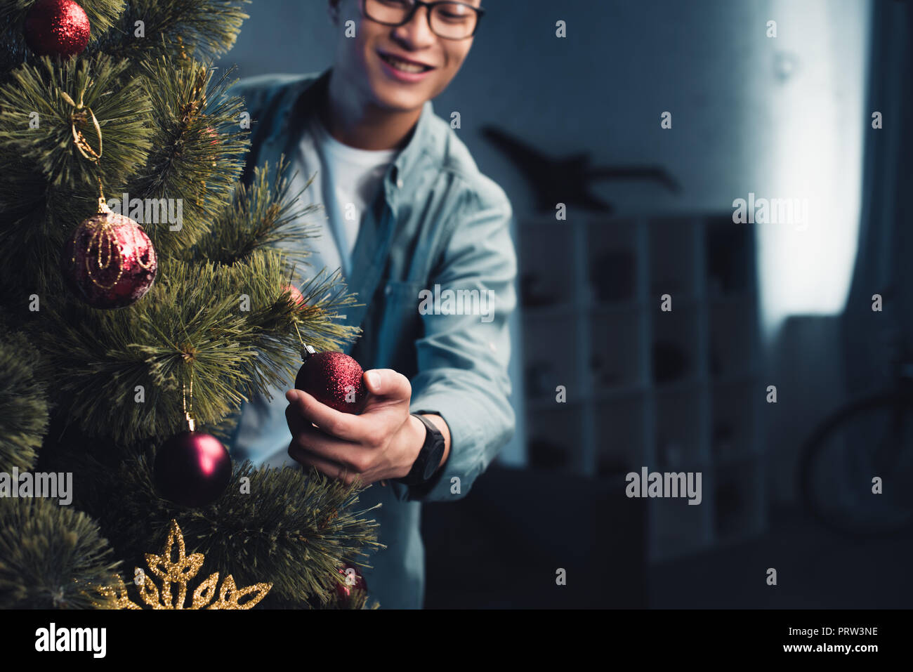 cropped shot of happy young asian man decorating christmas tree at home Stock Photo