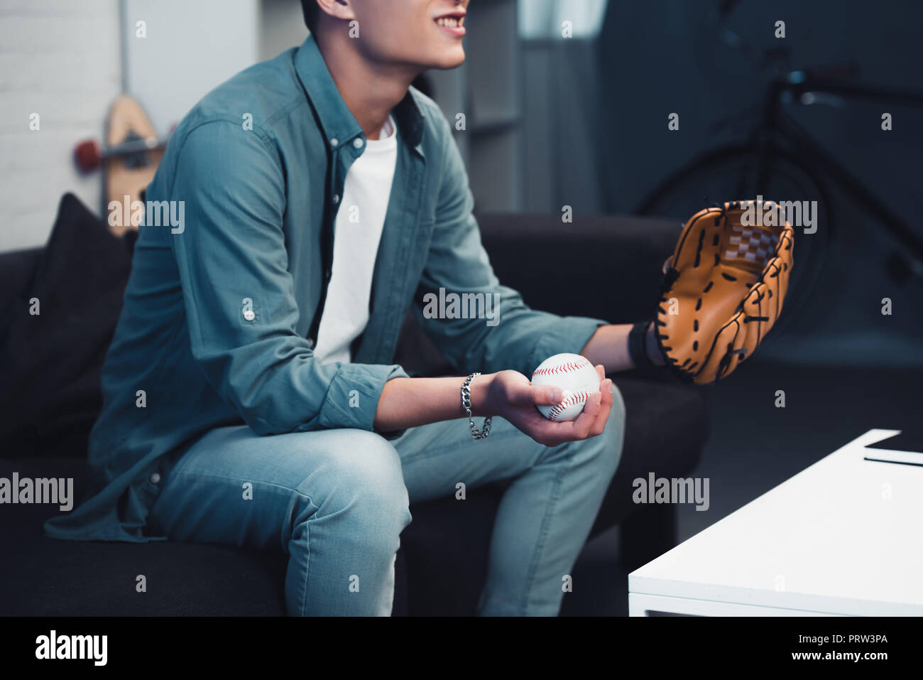 Cropped Shot Of Young Man With Baseball Glove And Ball Sitting On