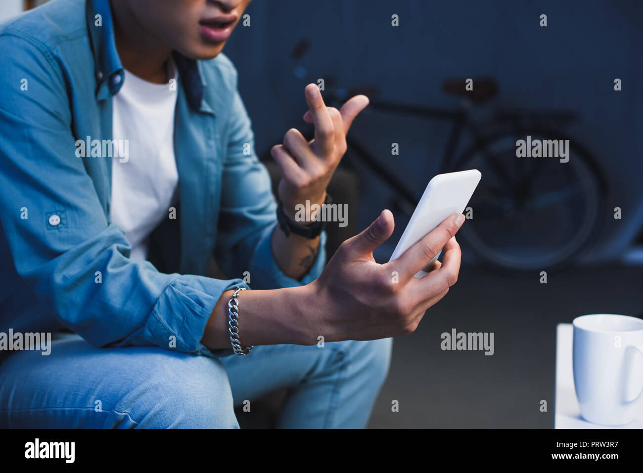 cropped shot of young asian man using smartphone and giving middle finger Stock Photo