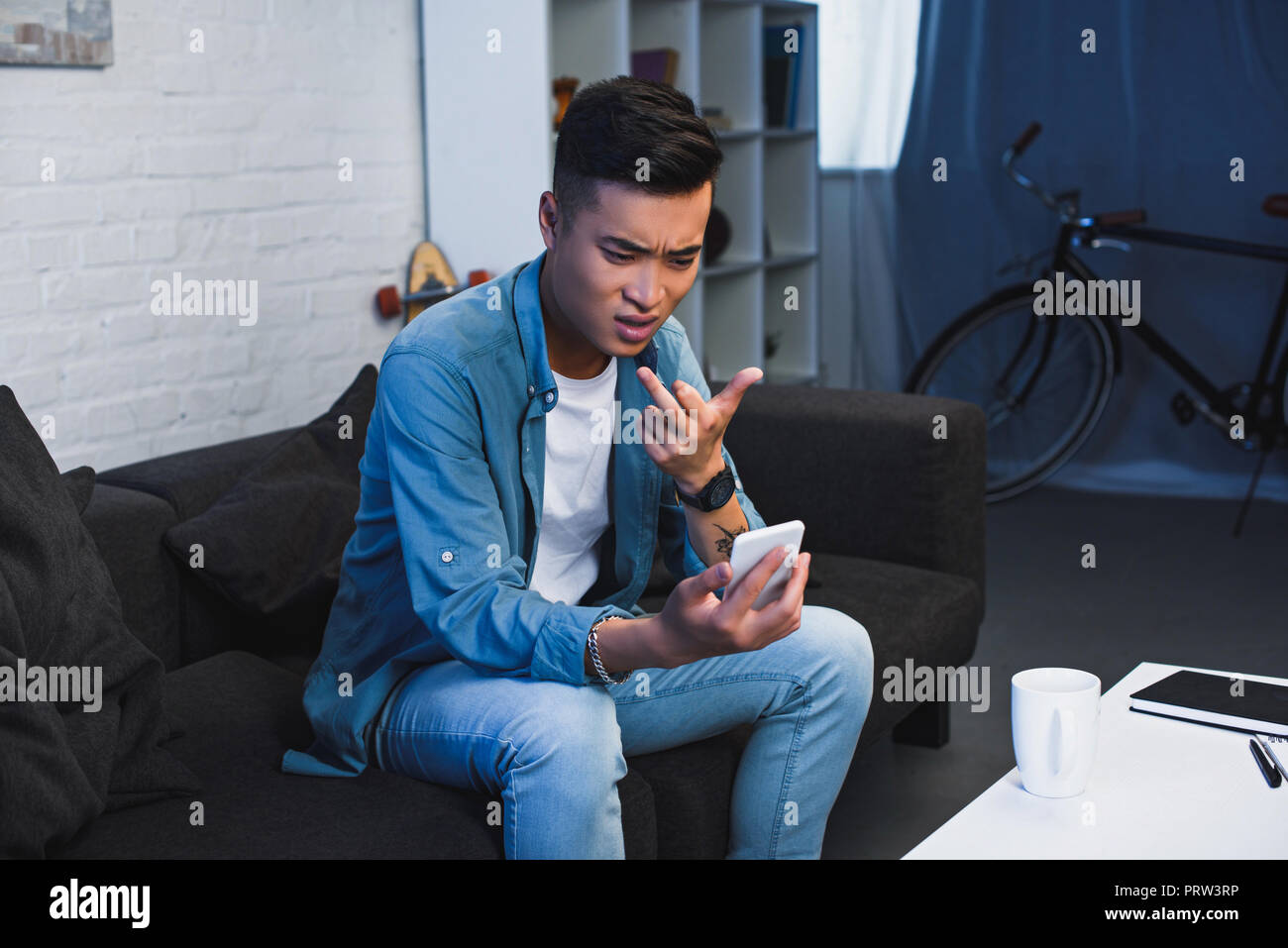 young asian man using smartphone and giving middle finger Stock Photo