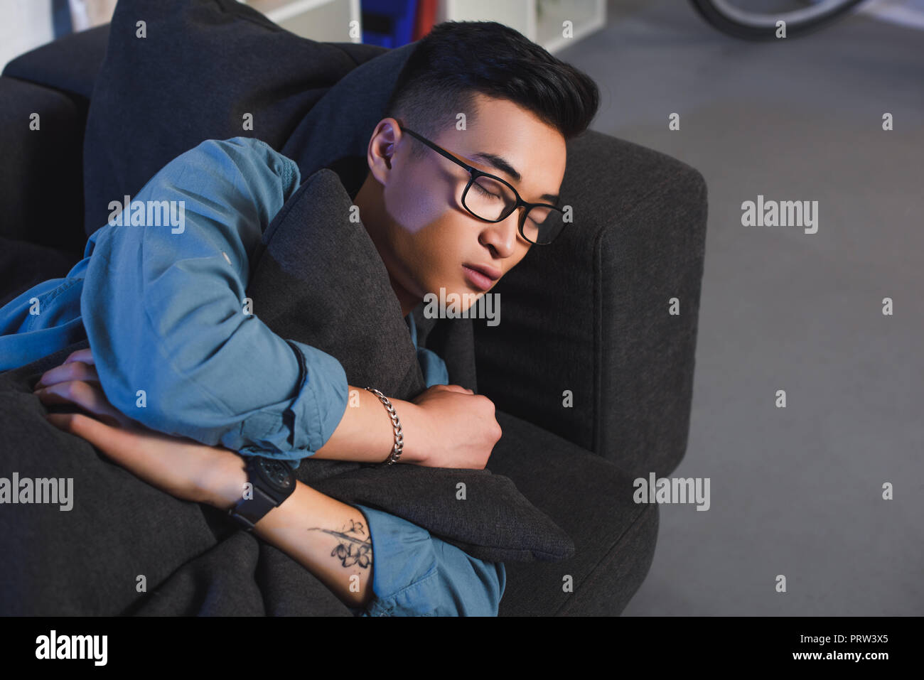 high angle view of young asian man in eyeglasses sleeping on sofa at home Stock Photo