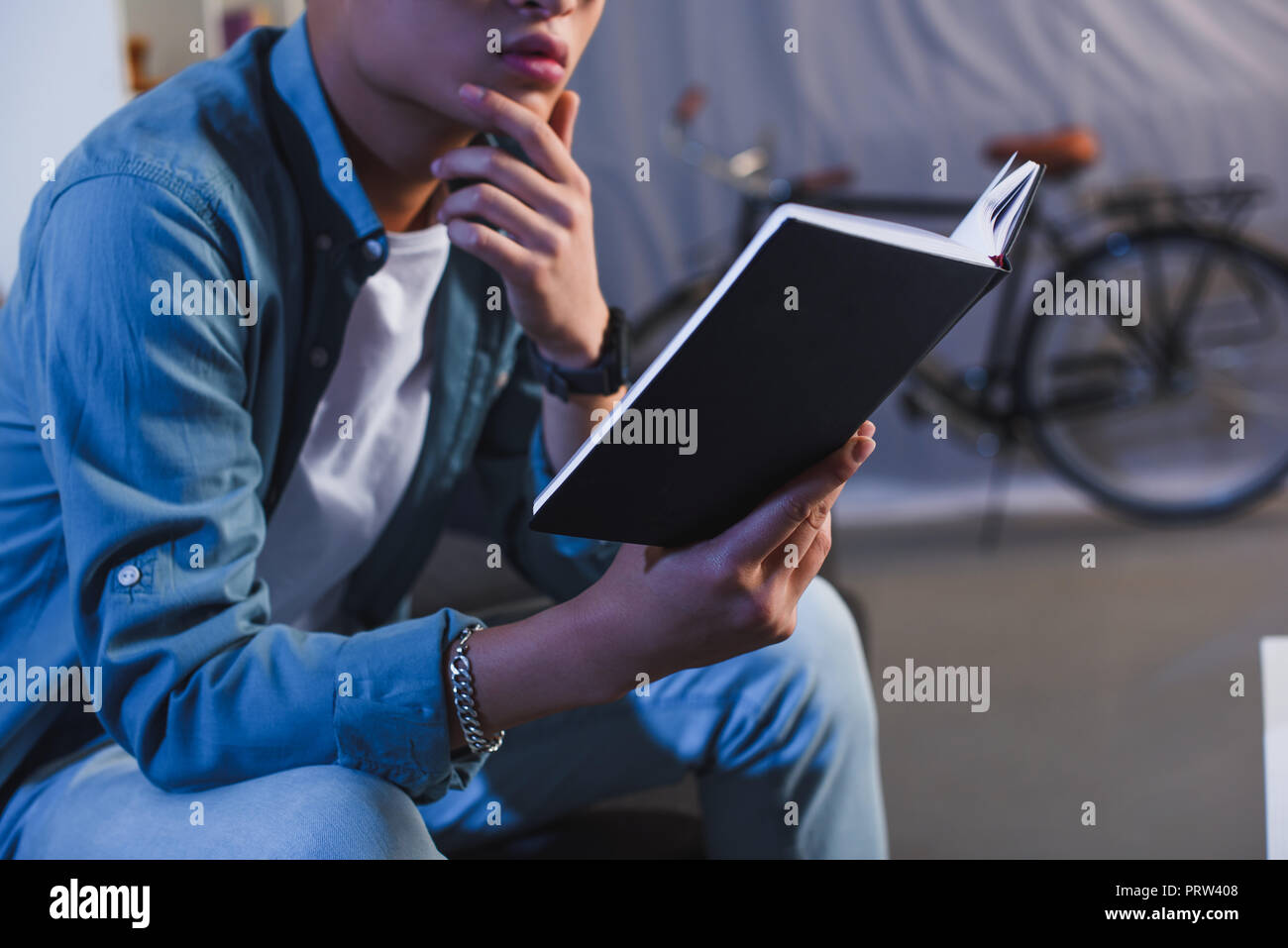 cropped shot of thoughtful young man reading book at home Stock Photo