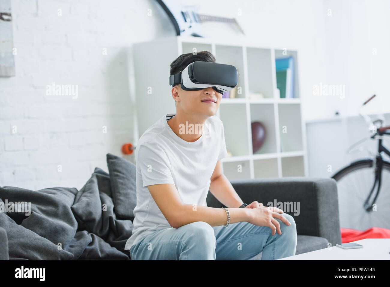 smiling young asian man using virtual reality headset at home Stock Photo