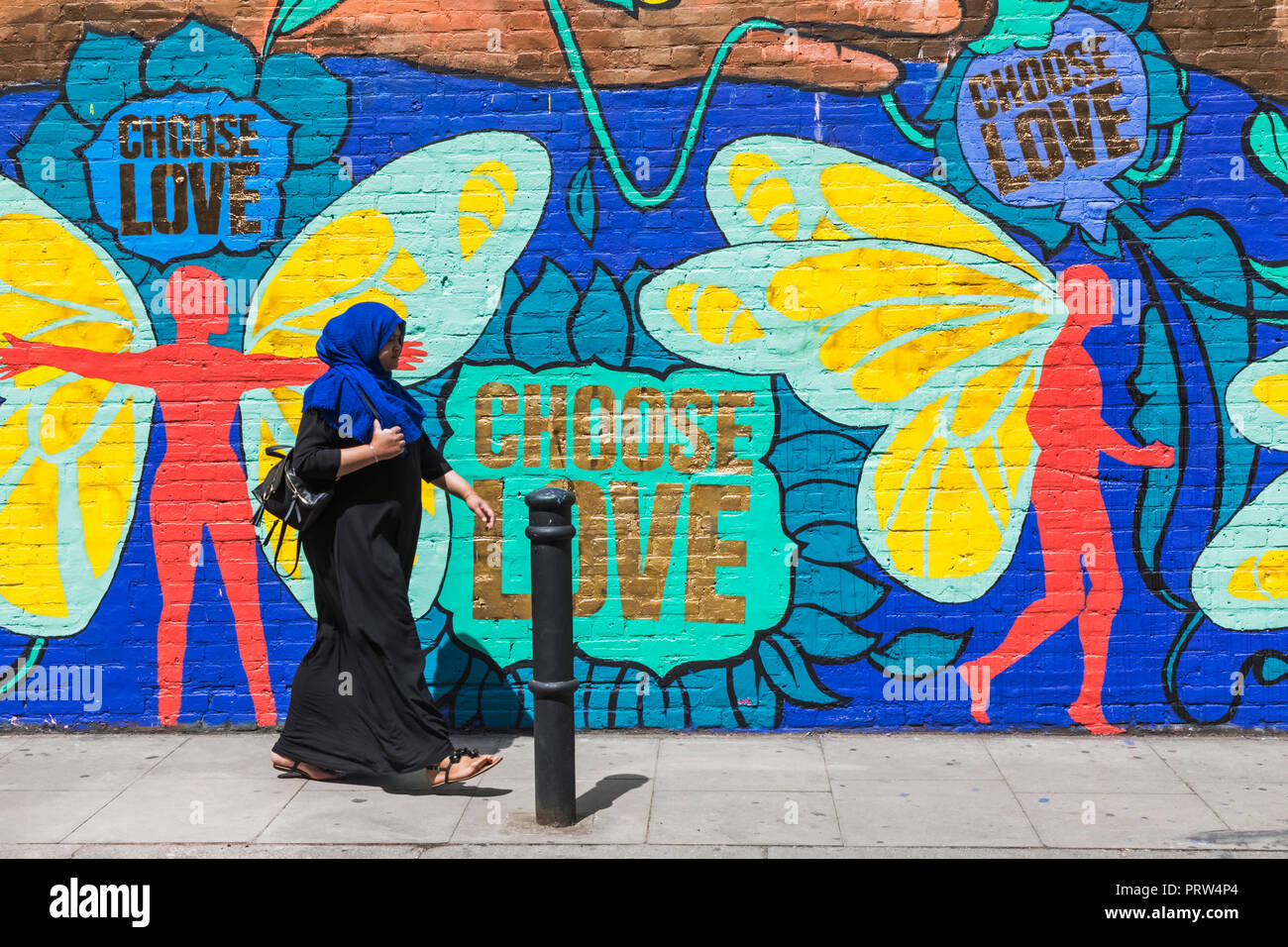 England, London, Shoreditch, Brick Lane, Muslim Lady Walking Past Street Art Stock Photo