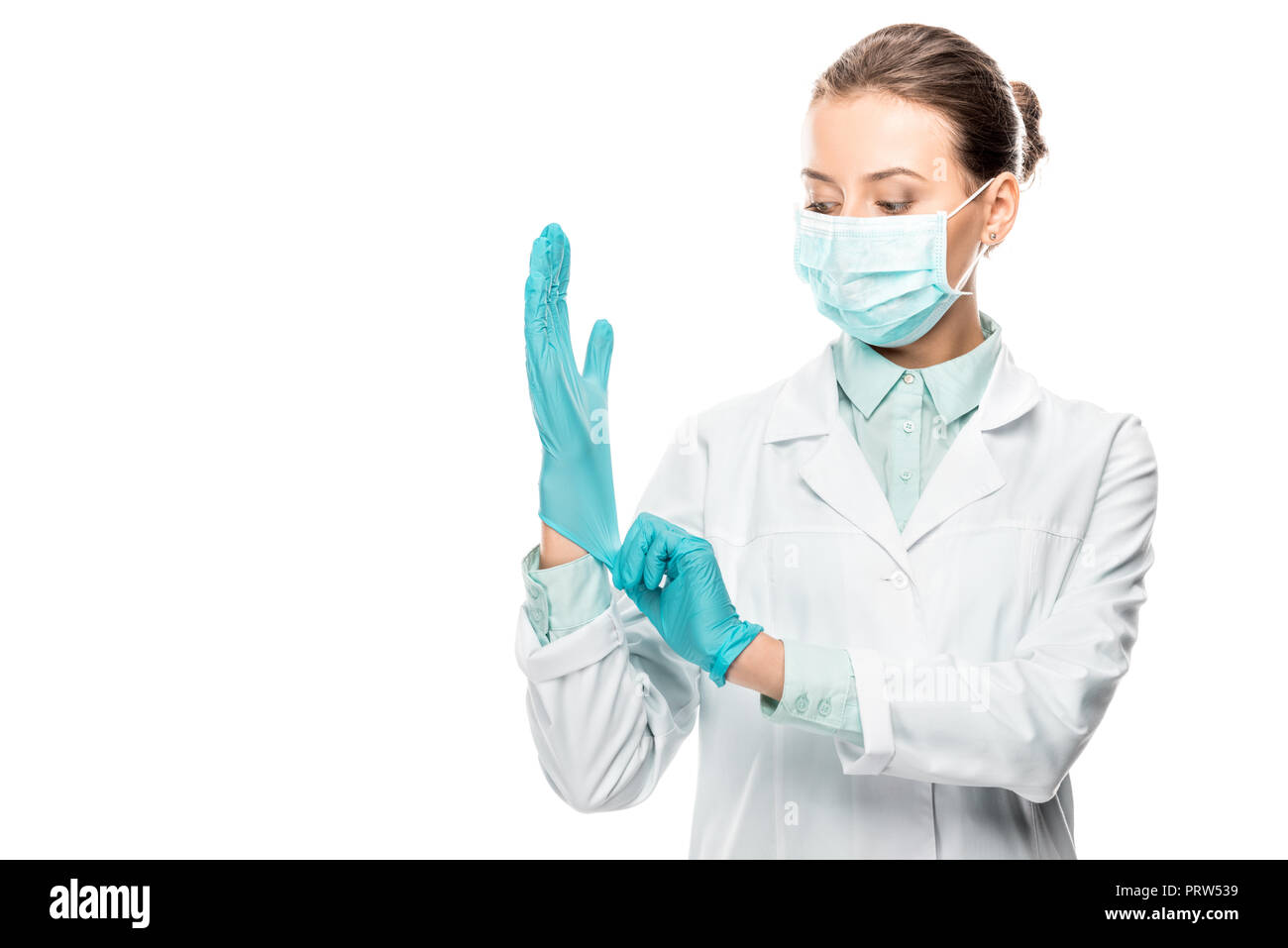 young female doctor in medical mask putting on latex gloves isolated on white Stock Photo