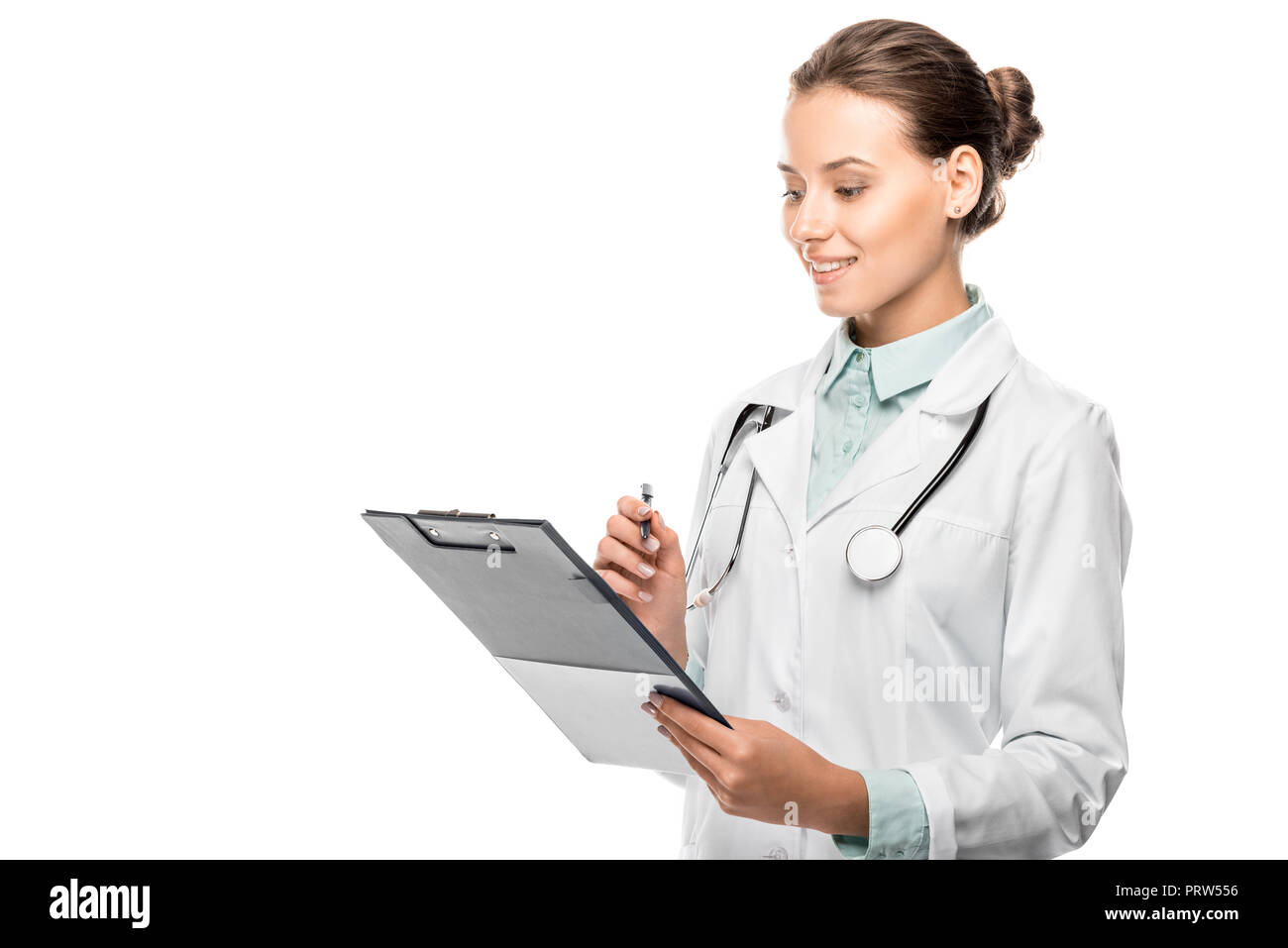 happy young female doctor in medical coat writing in clipboard isolated on white Stock Photo