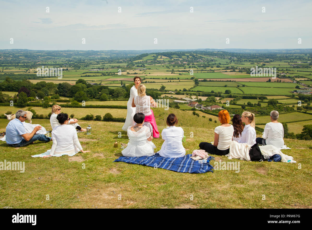Woman preforming faith and spiritual healing by the laying on of hands to a group of people on top of Glastonbury Tor Somerset England UK Stock Photo