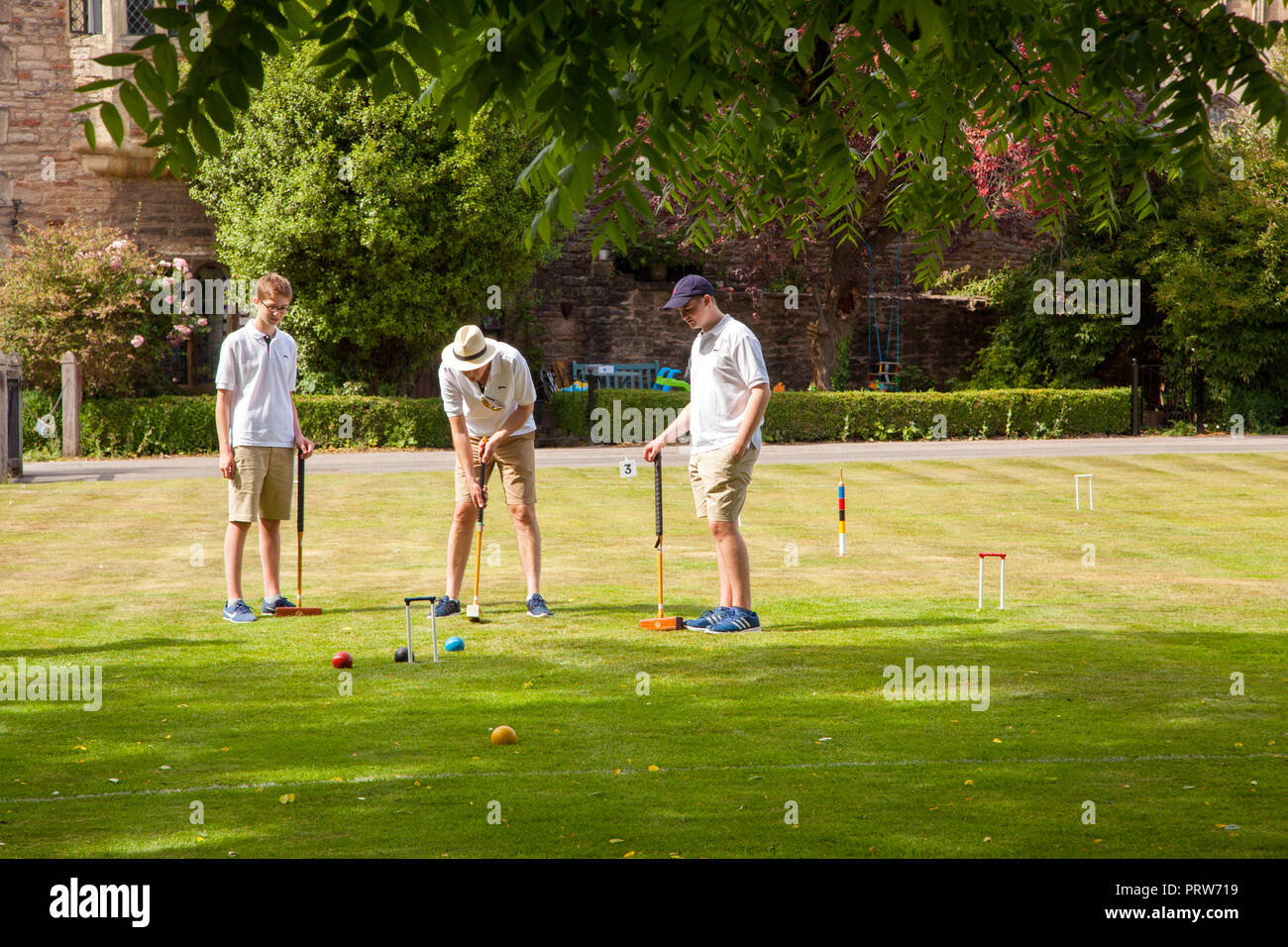 Men playing the nobble game of Croquet in the grounds of the Bishops Palace at Wells Cathedral in Somerset England UK Stock Photo