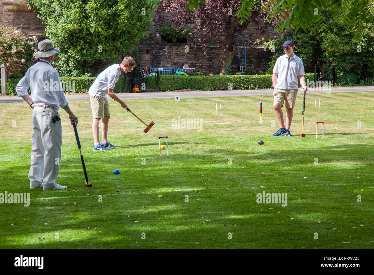 Men playing the nobble game of Croquet in the grounds of the Bishops Palace at Wells Cathedral in Somerset England UK Stock Photo