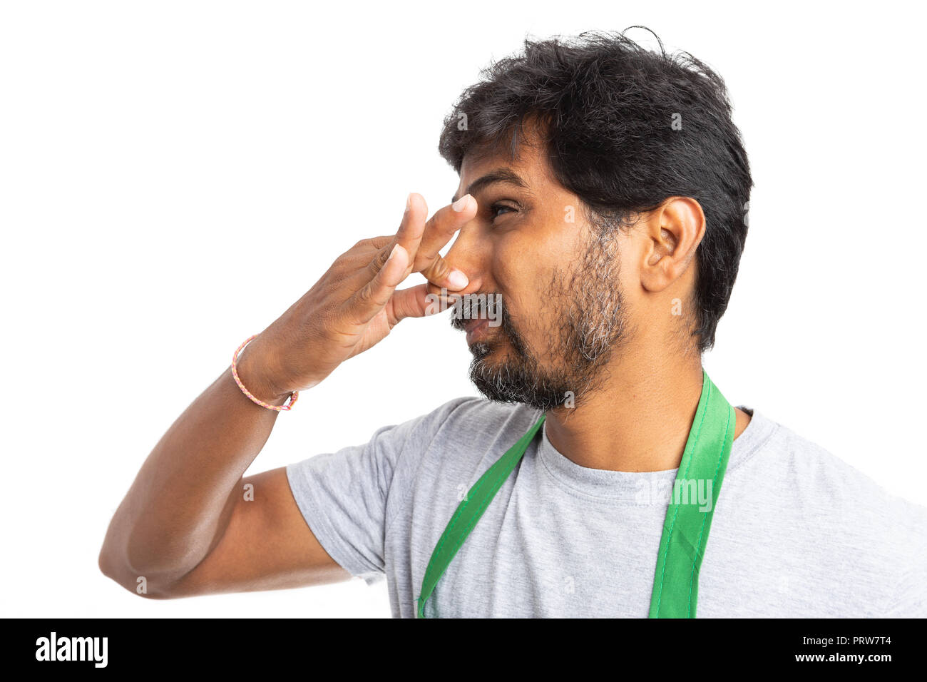 Disgusted supermarket or hypermarket employee holding nose with hand with repulsive expression isolated on white studio background Stock Photo
