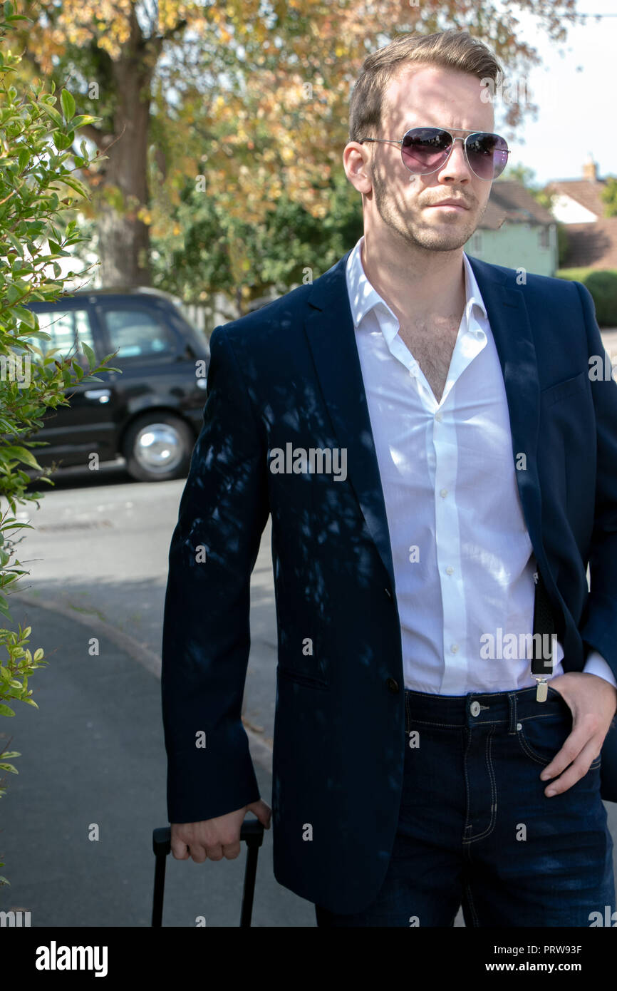 Handsome stylish businessman with white shirt, blazer and jeans walking  down country road with overnight case after leaving black cab Stock Photo -  Alamy
