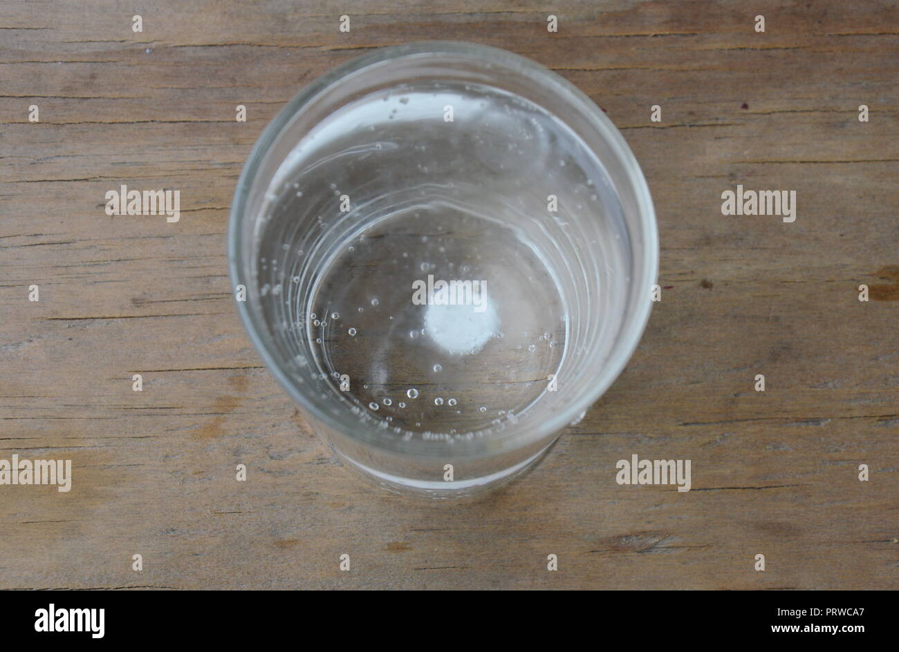 antacids in water glass on wooden table Stock Photo