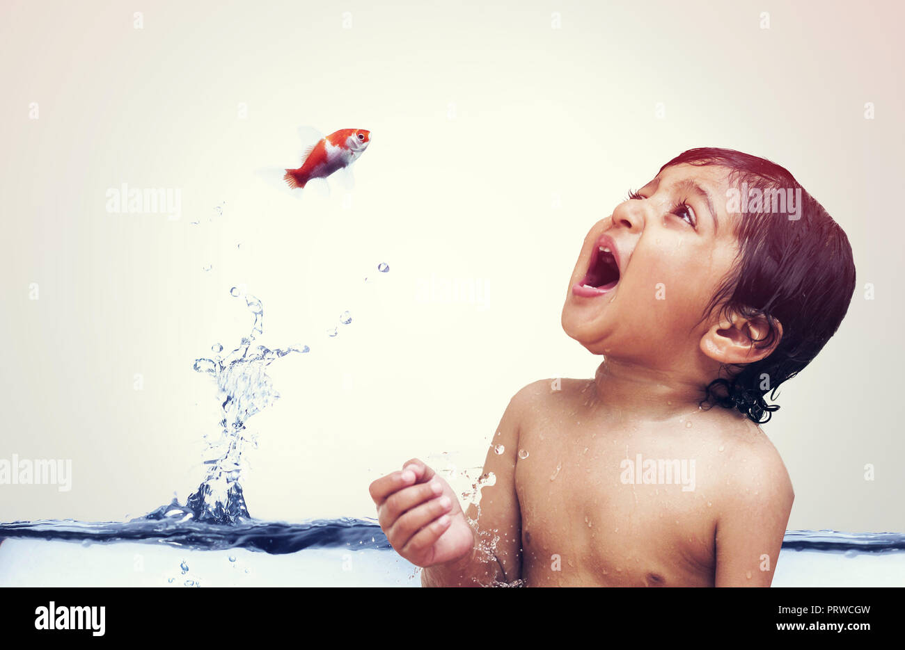 Goldfish jumping out of water directly into the kids mouth isolated on white Stock Photo