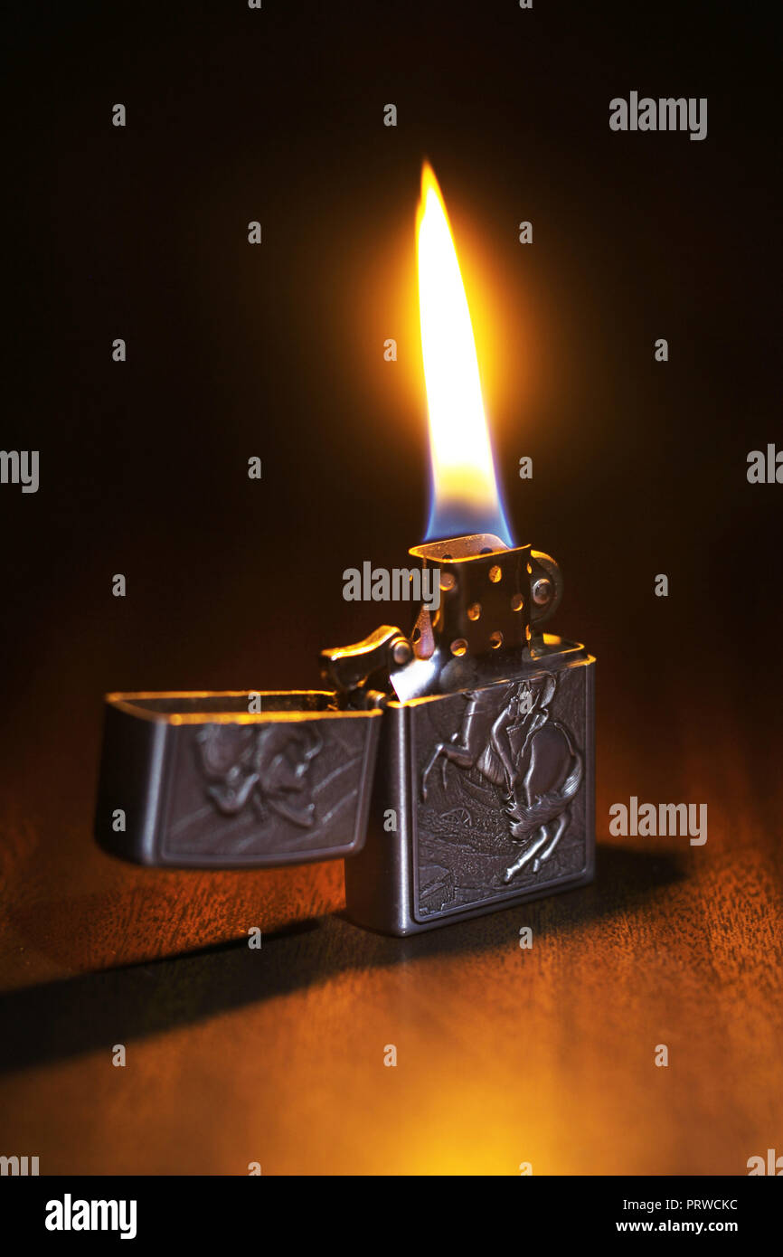 Beautiful lighter on a wooden floor igniting the dark room Stock Photo
