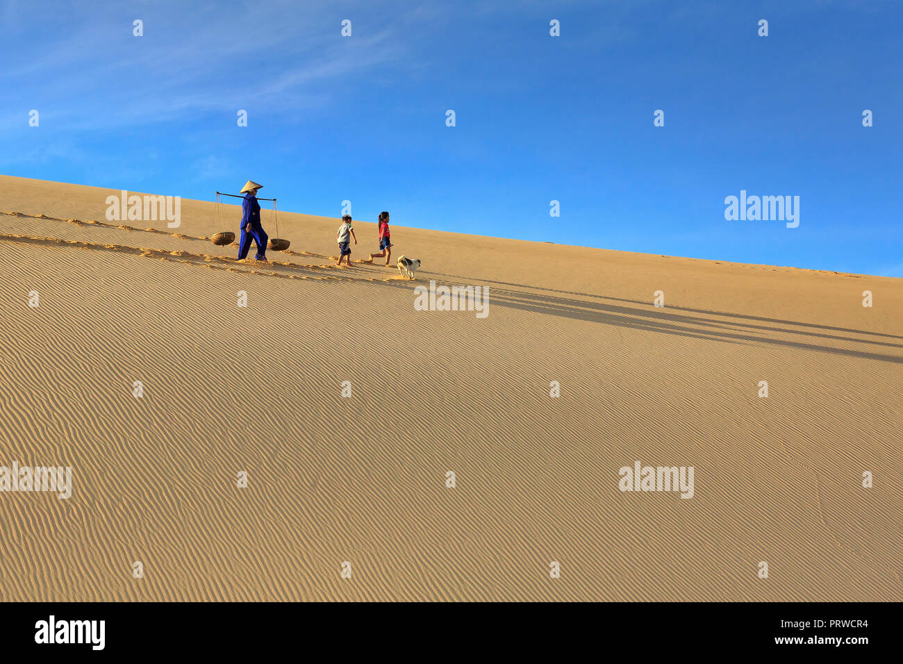woman carries a bamboo frame on the shoulder and two children walking ...