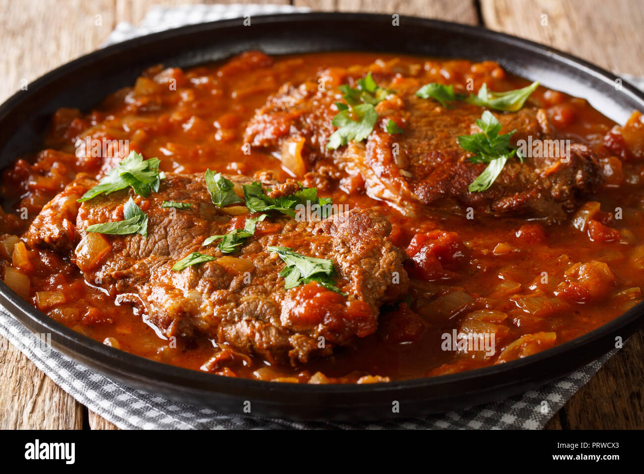 Delicious Swiss steak fried and then stewed in a spicy tomato sauce with vegetables close-up on the table. horizontal Stock Photo