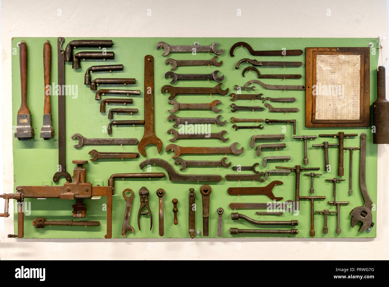 A carefully arranged tool board, in an old factory, rusty spanners and