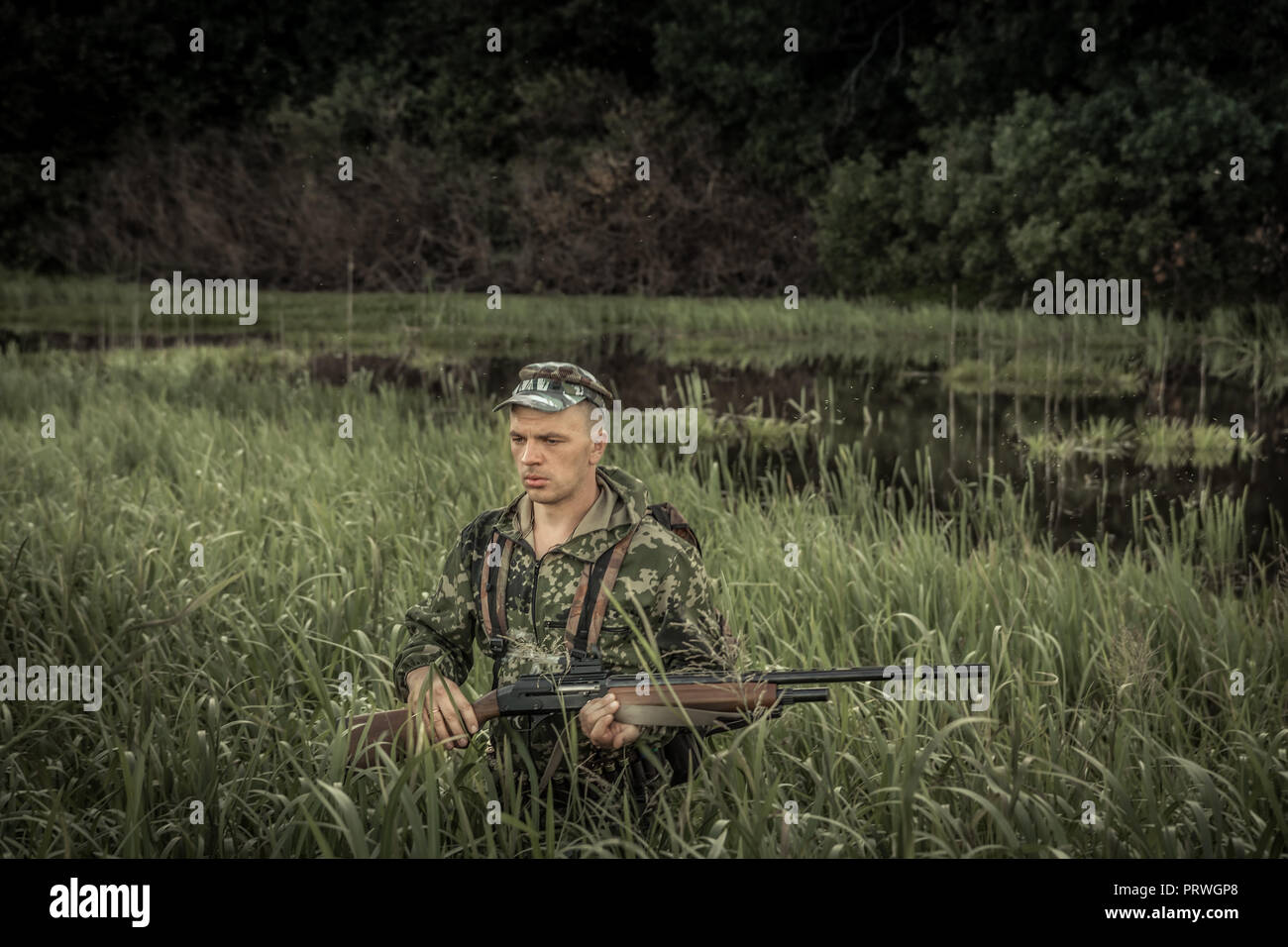 Hunting hunter brutal man breaking through swamp tall grass during hunting season Stock Photo