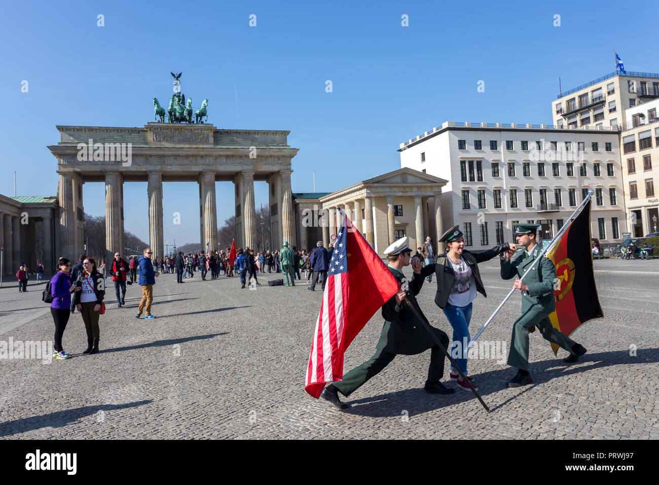 Young female tourist posing with American and Russian soldier in front of Berlin Gate or Brandenburger tor. Stock Photo