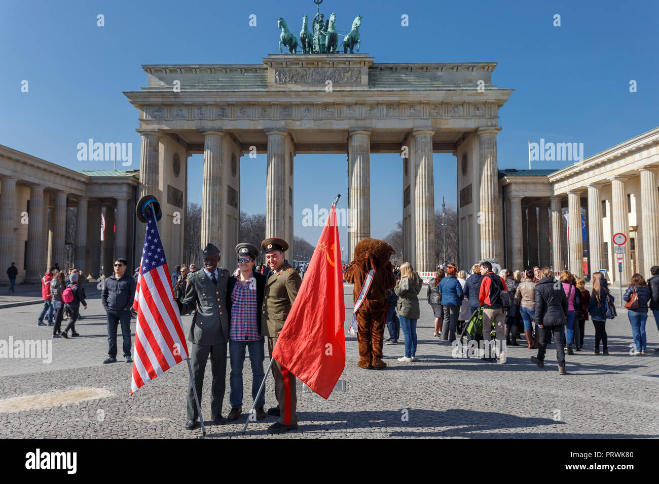 Young female tourist posing with American and Russian soldier in front of Berlin Gate or Brandenburger tor. Stock Photo