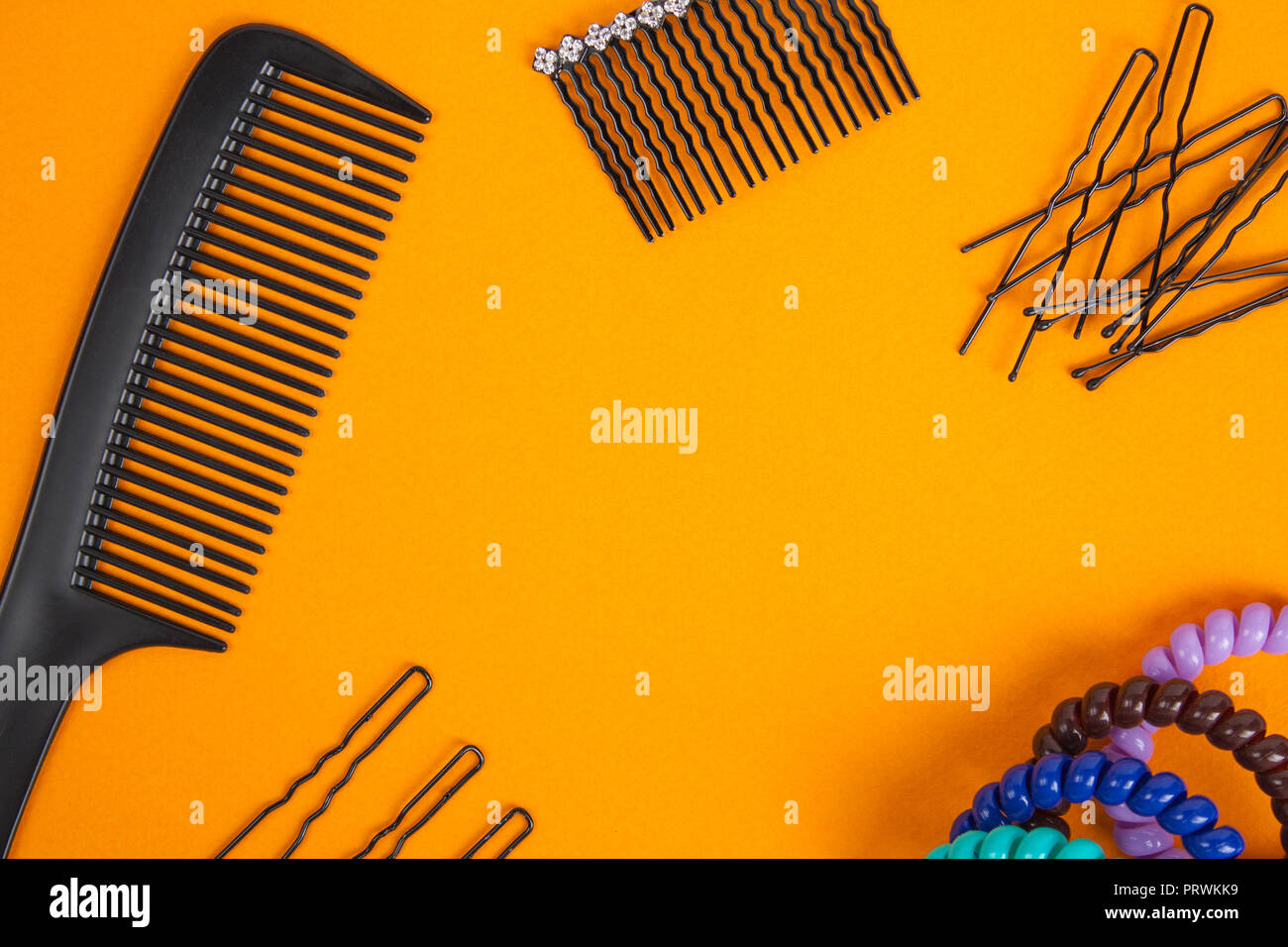 Hairbrush, barrette, hairpins and hair bands lies on orange background. Flat lay. Stock Photo