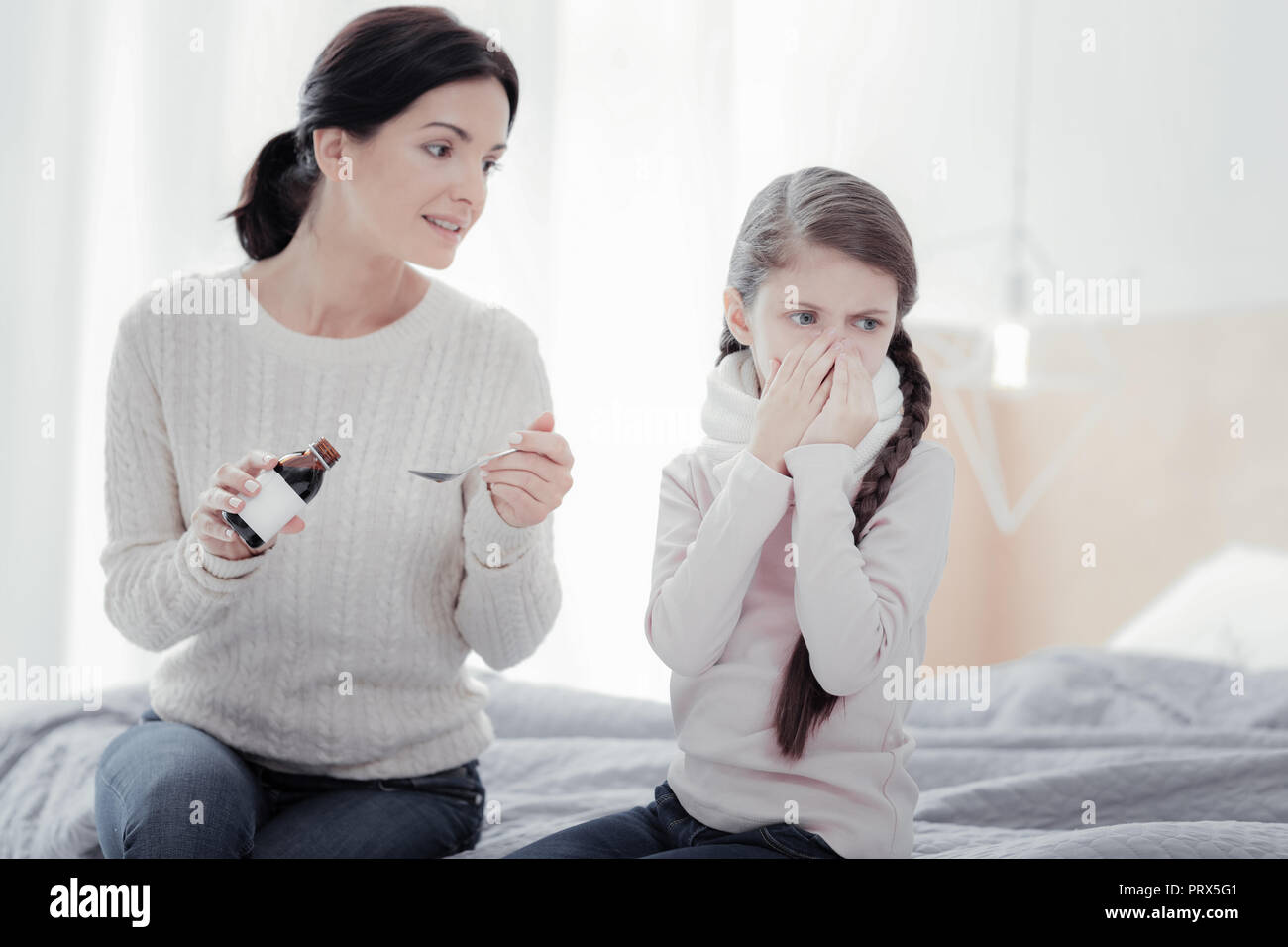 Positive mother bringing cough syrup for her daughter Stock Photo