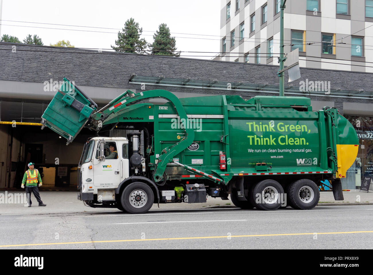 Green clean energy solid waste management garbage truck lifting a dumpster, Vancouver, BC, Canada Stock Photo