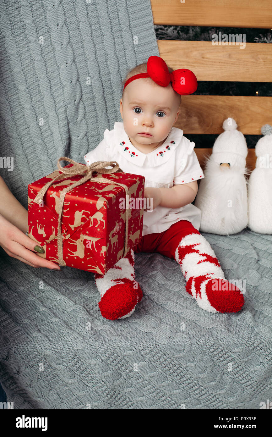 Little Baby Girl With Christmas Present On Bench With Knitted
