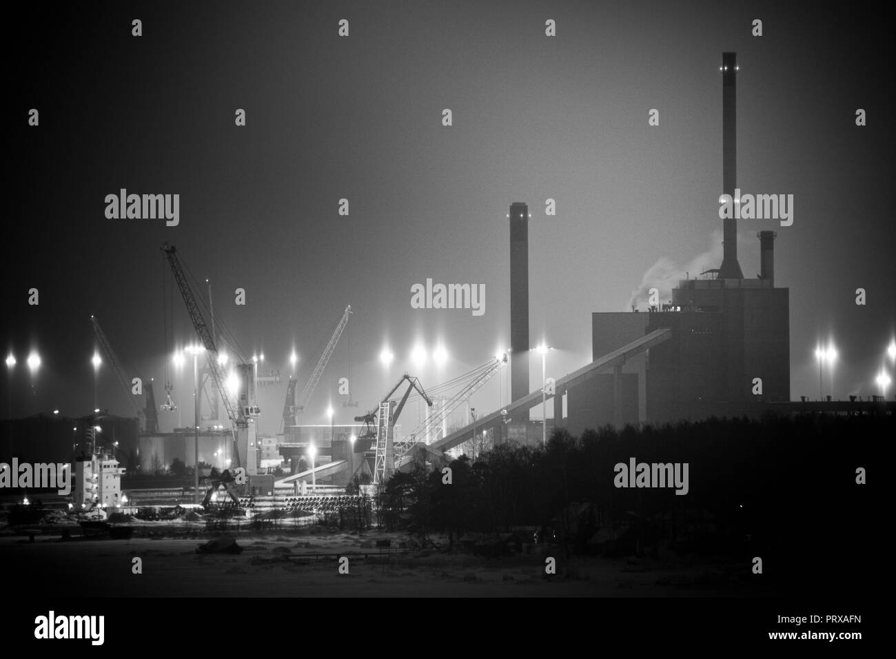 Silhouettes of power plant, chimneys and port cranes on a winter night Stock Photo
