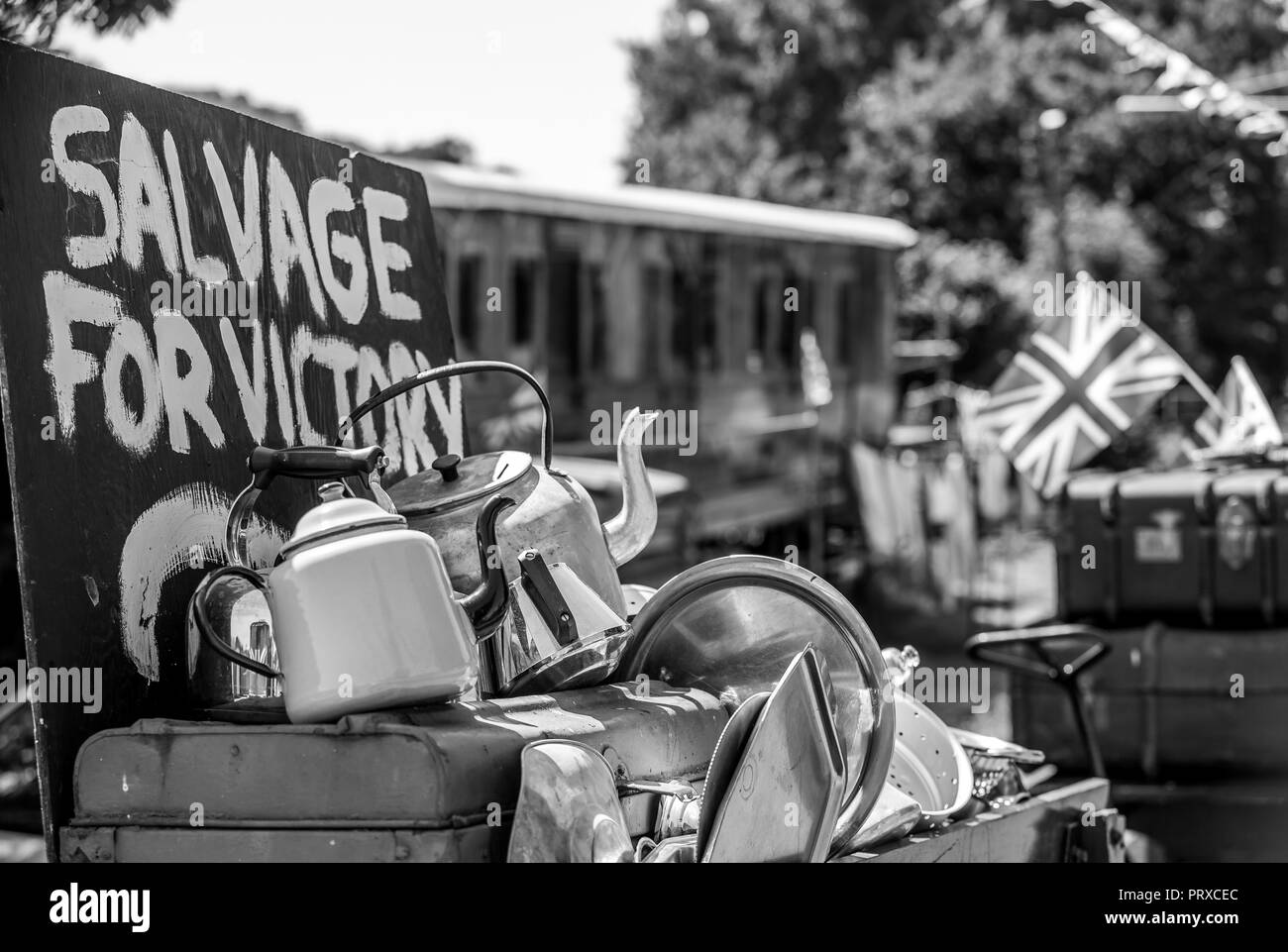 Black & white close up, Salvage for Victory sign & old metal tea pots, kettles pots & pans. 1940's WW2 wartime event, Severn Valley Railway, summer. Stock Photo