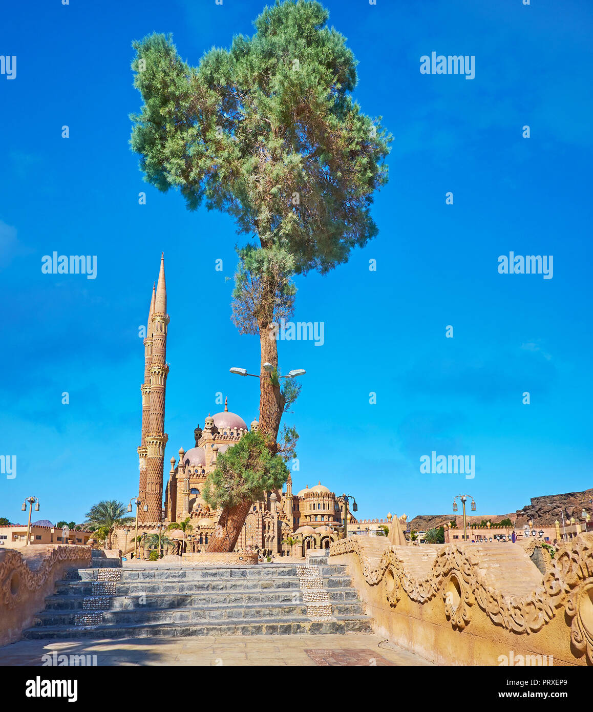 The tall palm tree hides the picturesque Al Sahaba (Al Mustafa) mosque - the famous modern landmark of Sharm El Sheikh, Sinai, Egypt. Stock Photo