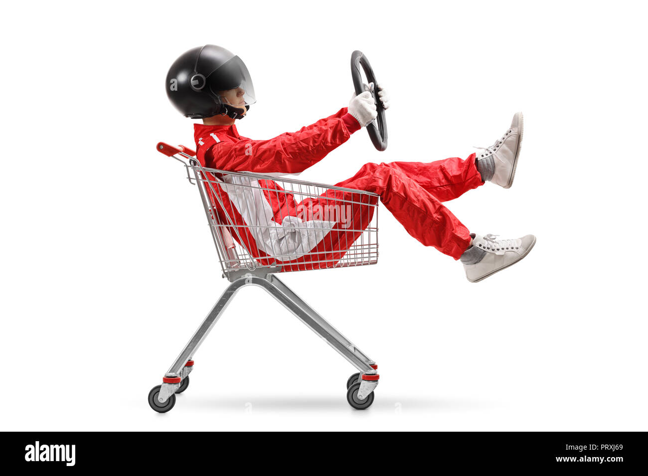 Guy in a racing suit with helmet holding a steering wheel and sitting inside a shopping cart isolated on white background Stock Photo