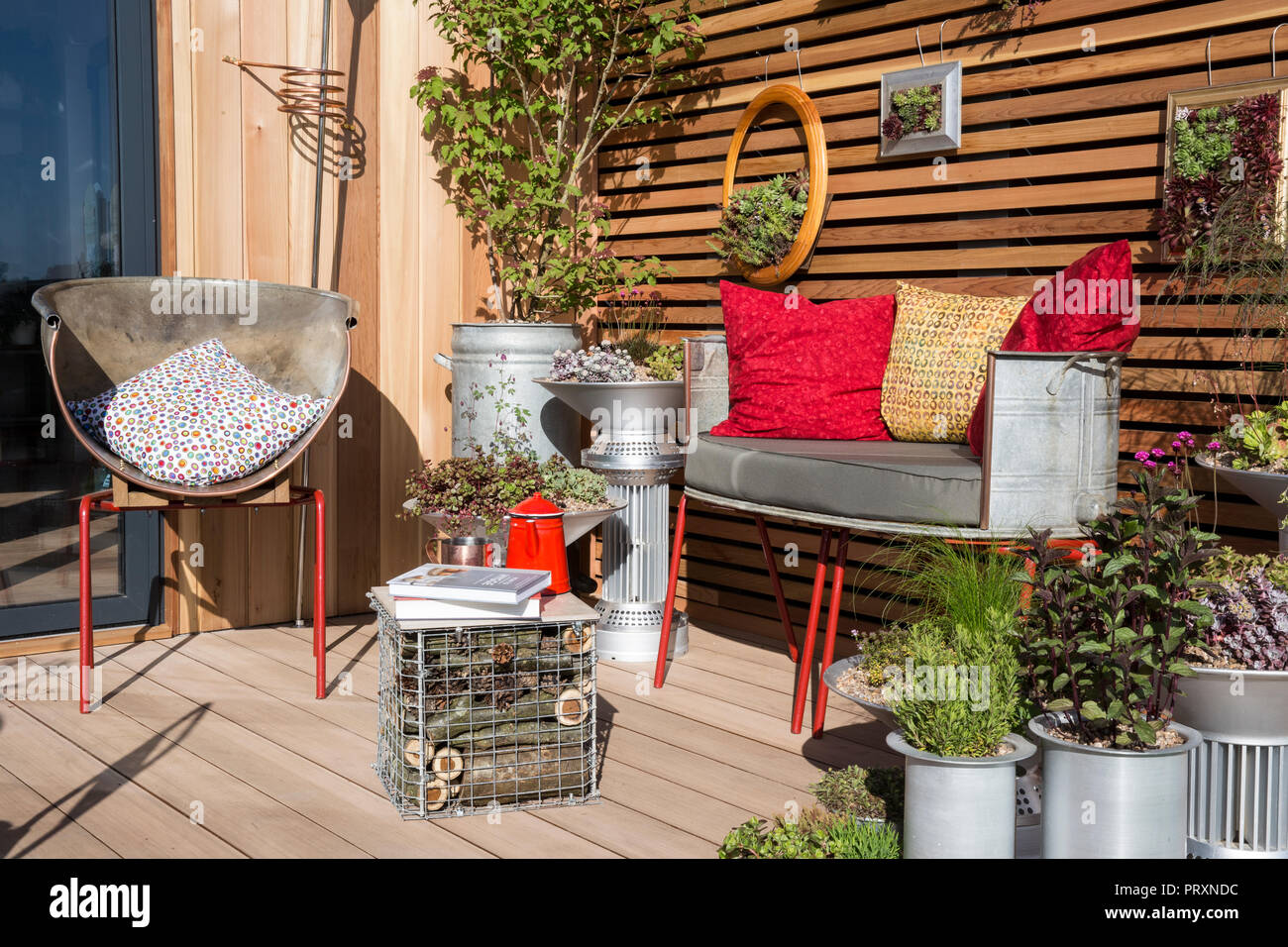 small space balcony garden with metal garden bench cushions repurposed unusual metal containers sempervivum succulent succulents plants display UK Stock Photo