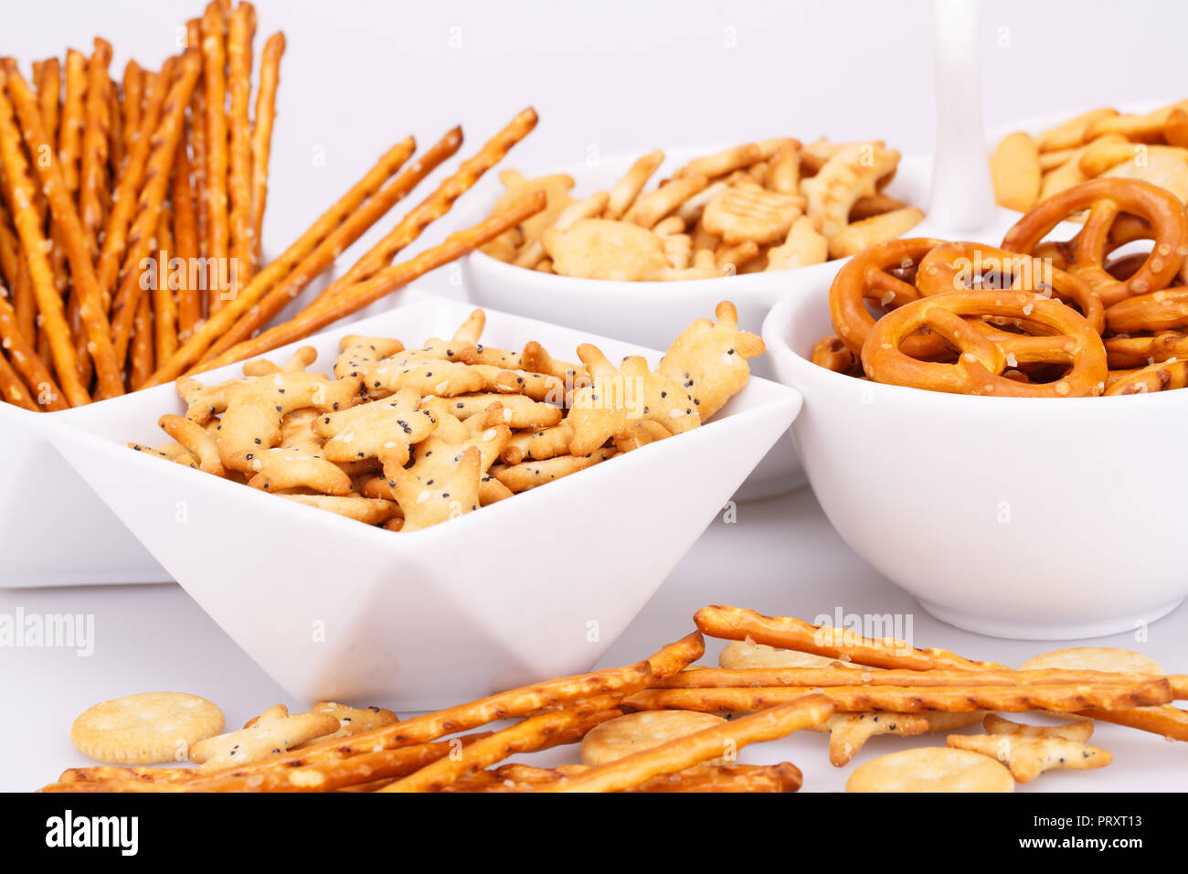 Different salted crackers in bowls on white background. Stock Photo