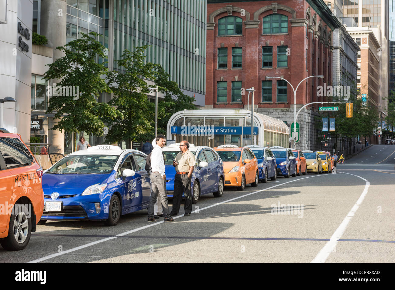 Queue of taxi cabs parked along the street curb waiting to be called for service as needed, Vancouver City. Stock Photo