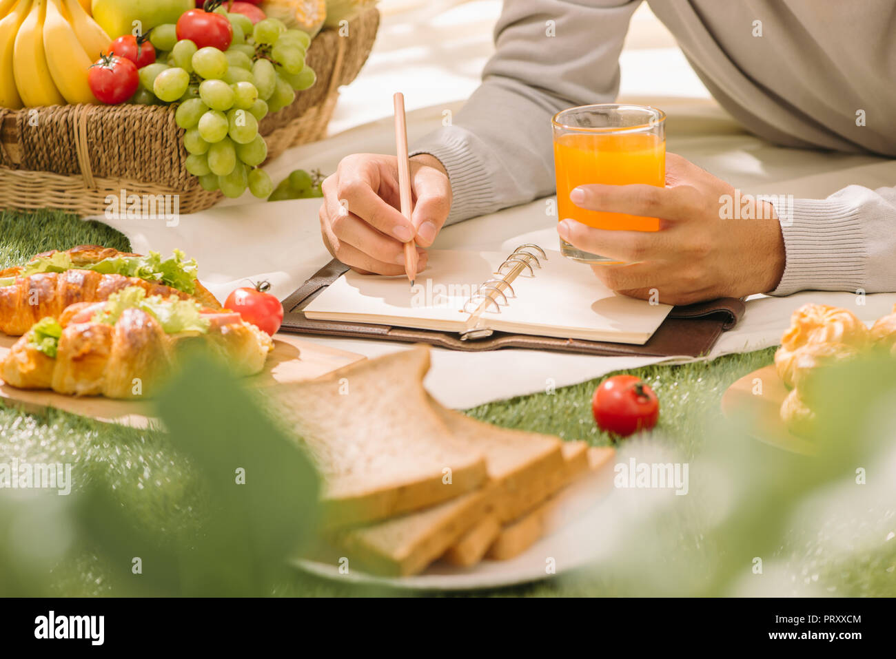 Picnic wicker basket with food, bread, fruit and orange juice on a red ...