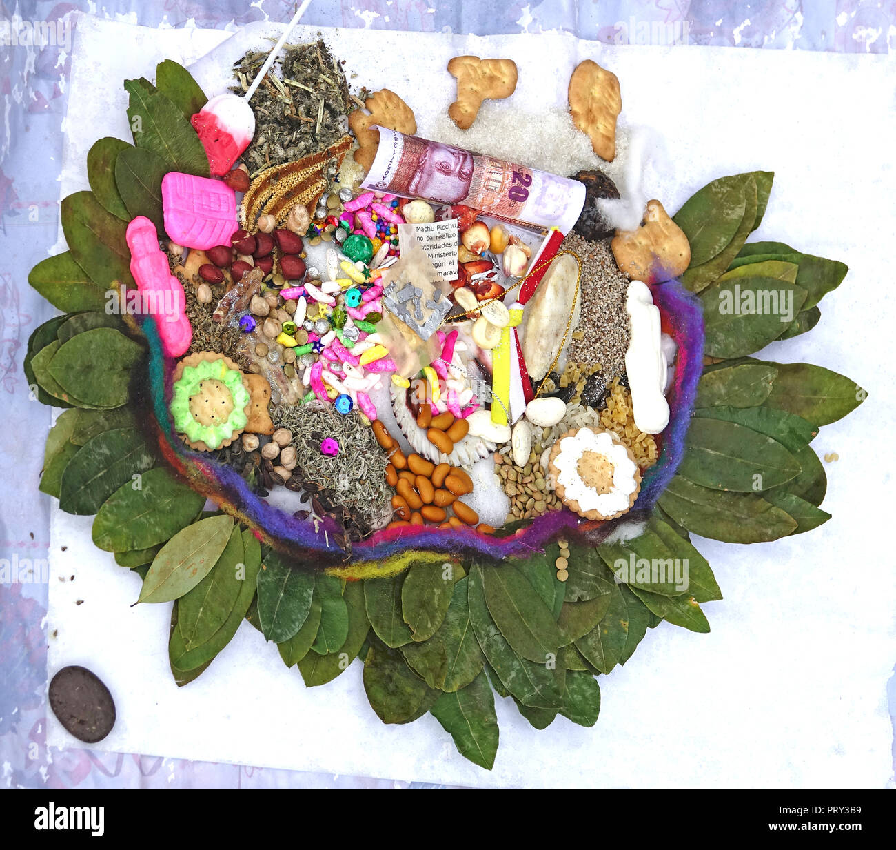 Peruvian shaman offering of food and trinkets surrounded by coca leaves