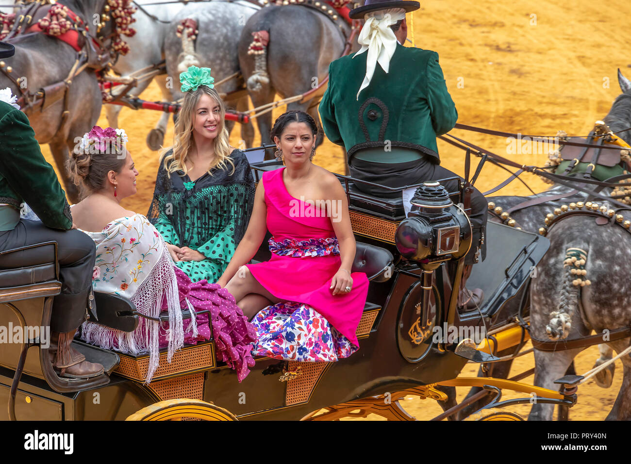 Seville, Spain - April  15, 2018: Young Women wearing traditional Sevillana dresses or flamenca dresses in a Horse drawn carriage in Seville April Fai Stock Photo