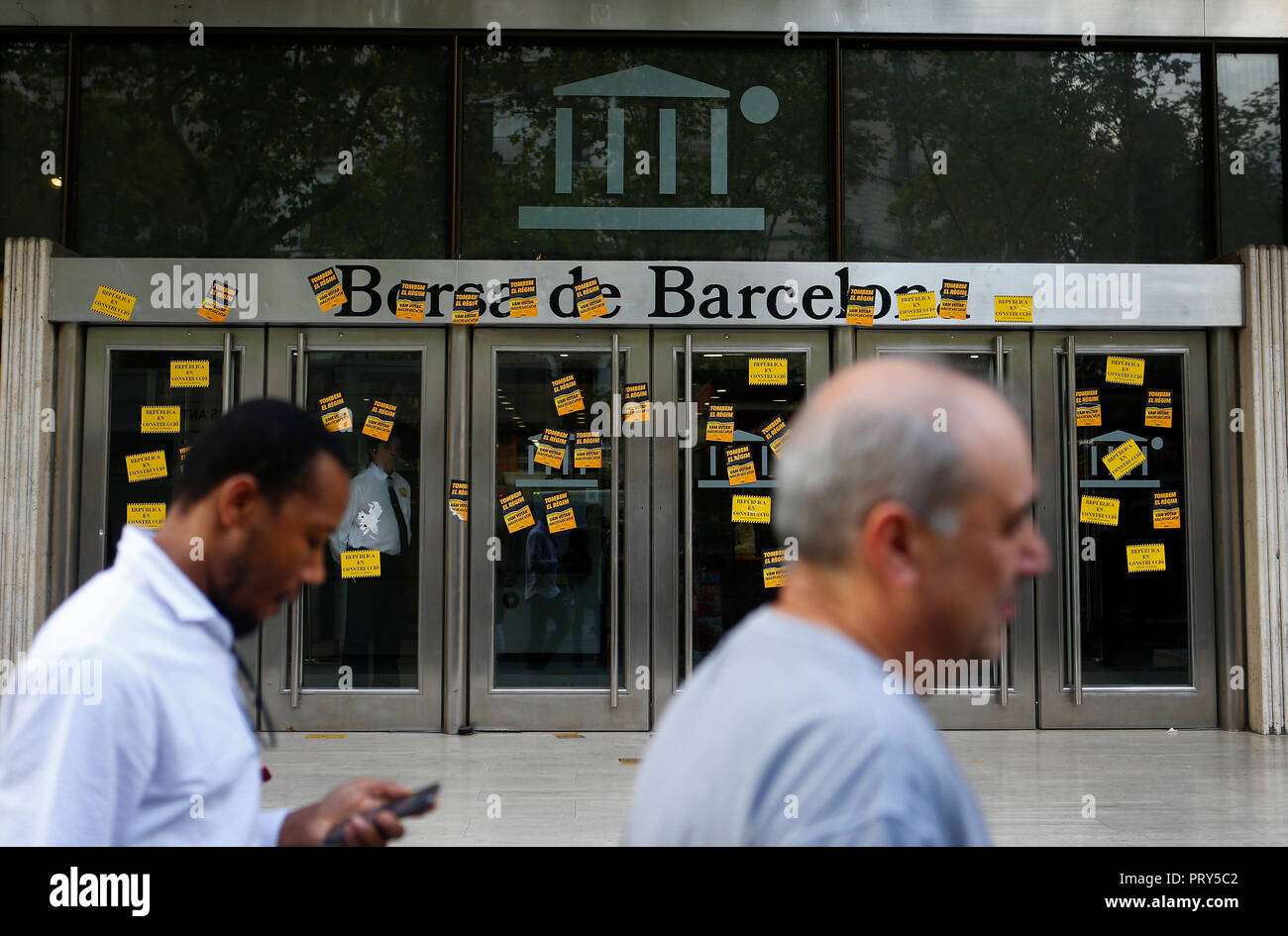 People walk next to Barcelona trade stock building covered with protest stickers during the 1st October protests in Catalonia Stock Photo