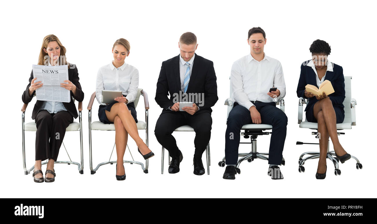 Group Of Businesspeople Doing Various Activities While Waiting For Job Interview Stock Photo