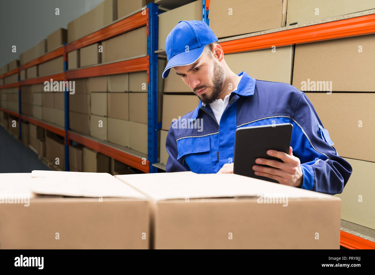 Young Delivery Man In Uniform Checking His Package On Digital Tablet Stock Photo