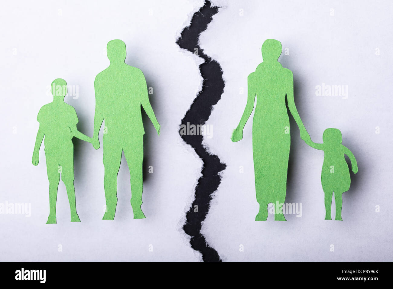 Close-up Of Family Separated By Crack On White Surface Stock Photo