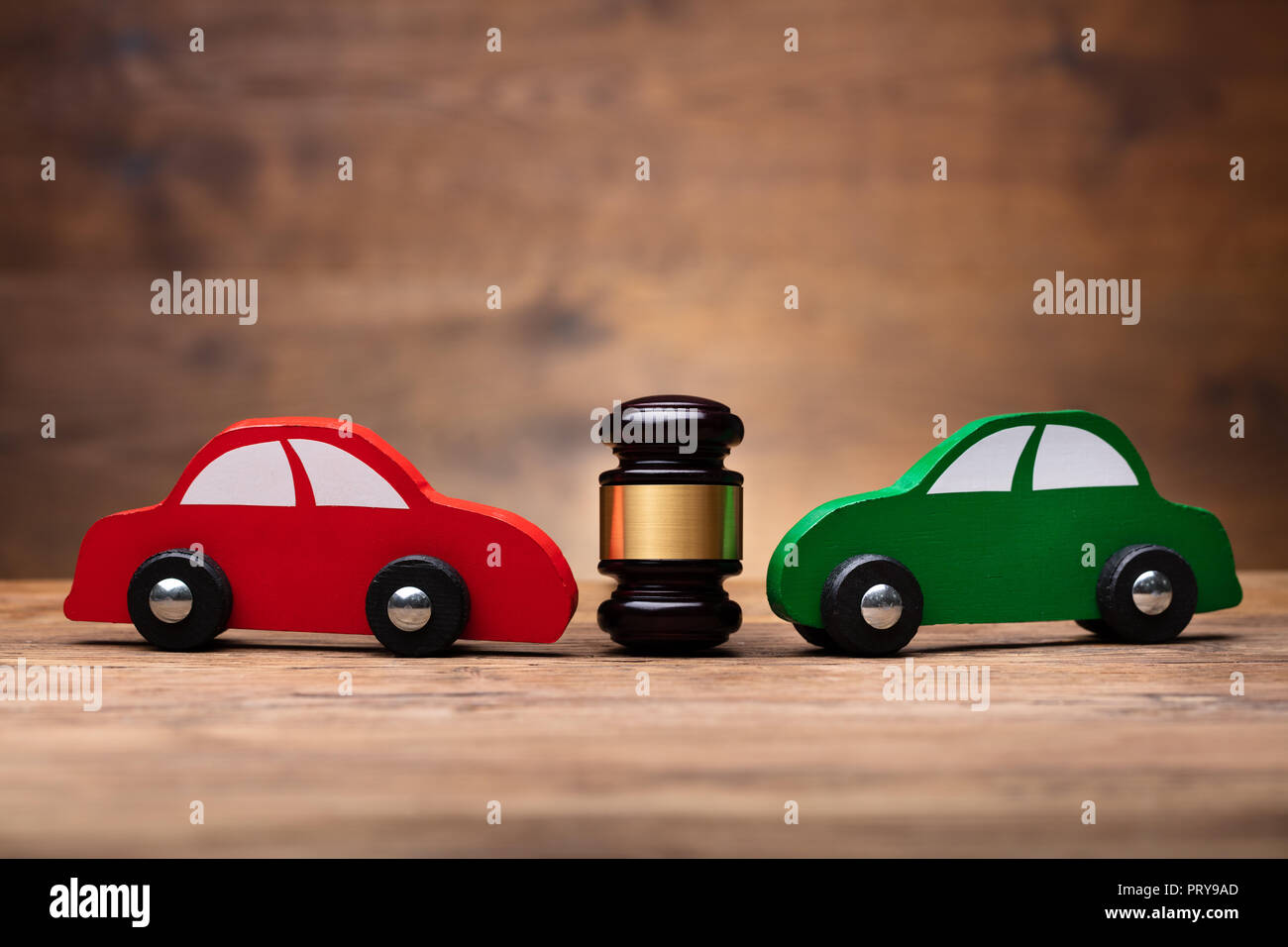 Wooden Mallet Between Two Red And Green Car On Wooden Surface Stock Photo