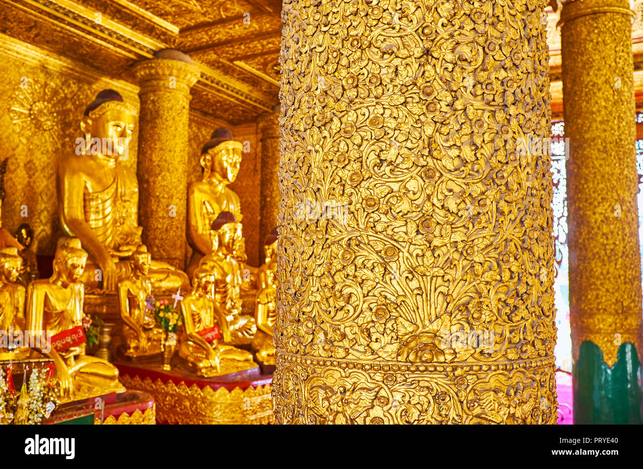 YANGON, MYANMAR - FEBRUARY 27, 2018:  Interior of Kassapa Buddha Image House with its masterpiece relief column, decorated with gilt plaster floral or Stock Photo