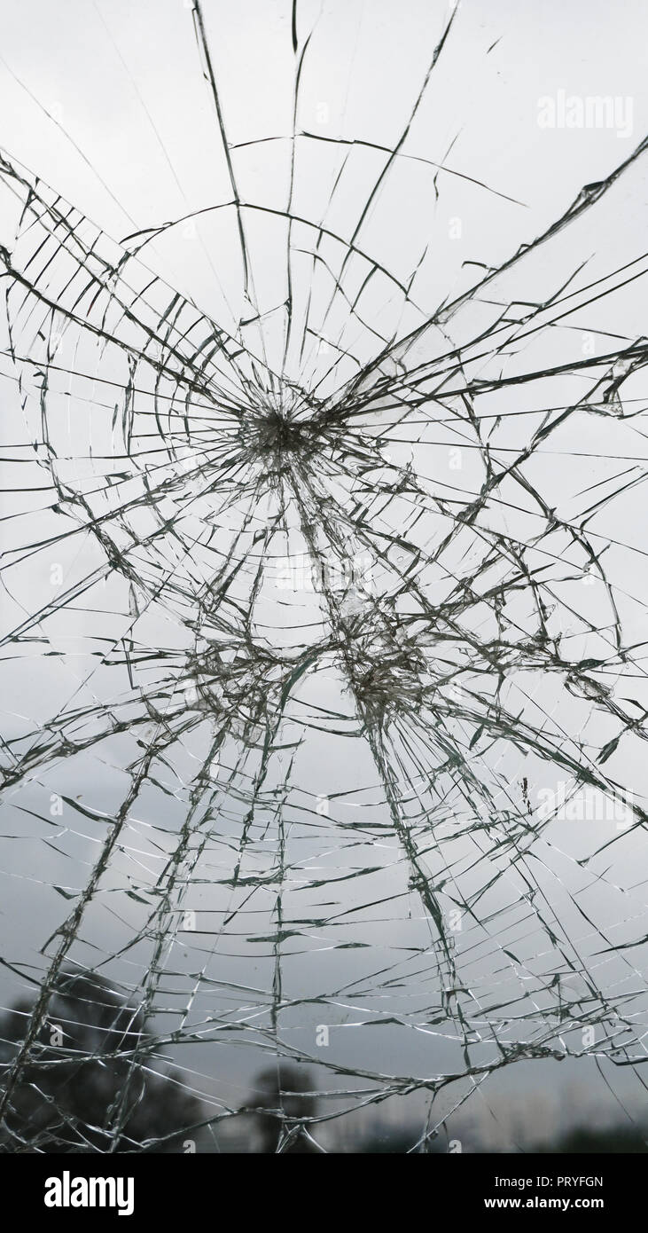 Broken glass in open space. Cloudy sky. Crack texture. Stock Photo