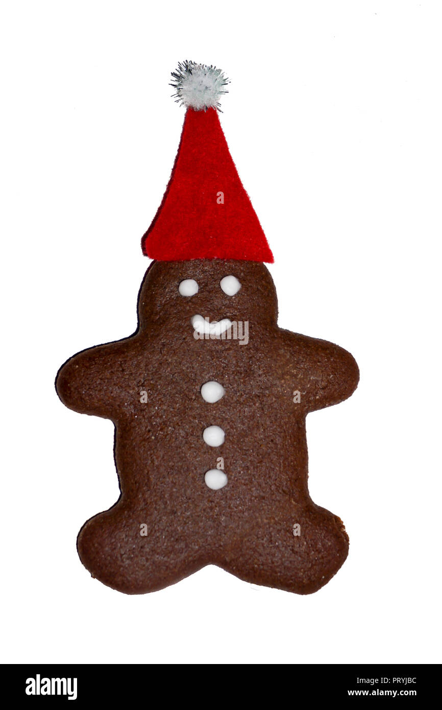 Gingerbread man cookie in Santa's red hat closeup, isolated, white background. Stock Photo