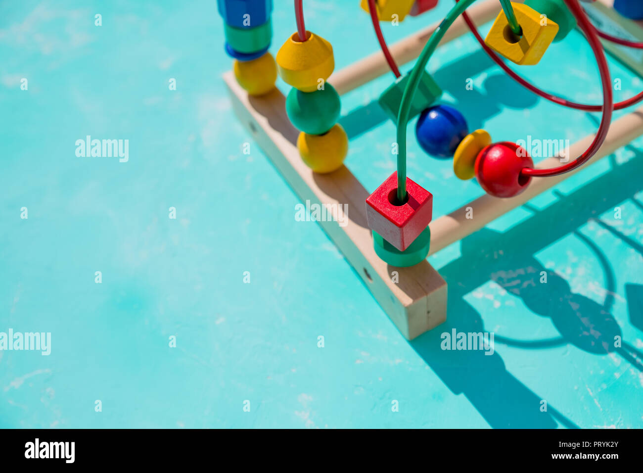 Children's toy labyrinth, maze on a metal spiral with ball, cylinder, cube on a wooden stand close-up.learning color and form in various shapes. Develops fine motor skills and logical thinking.Copy space Stock Photo