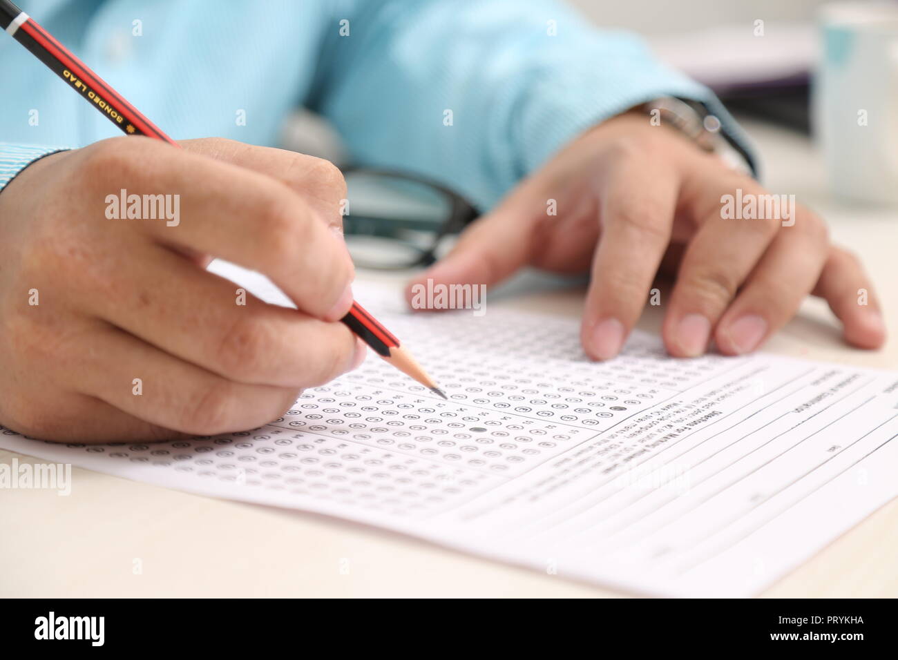Man hand holding pencil. Man hand on OMR sheet. Stock Photo