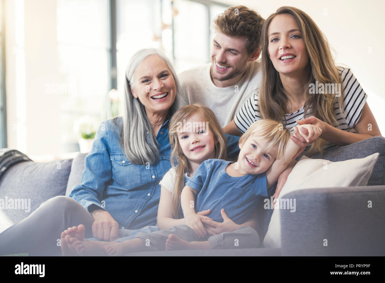 Extended family sitting on couch, smiling happily Stock Photo Alamy