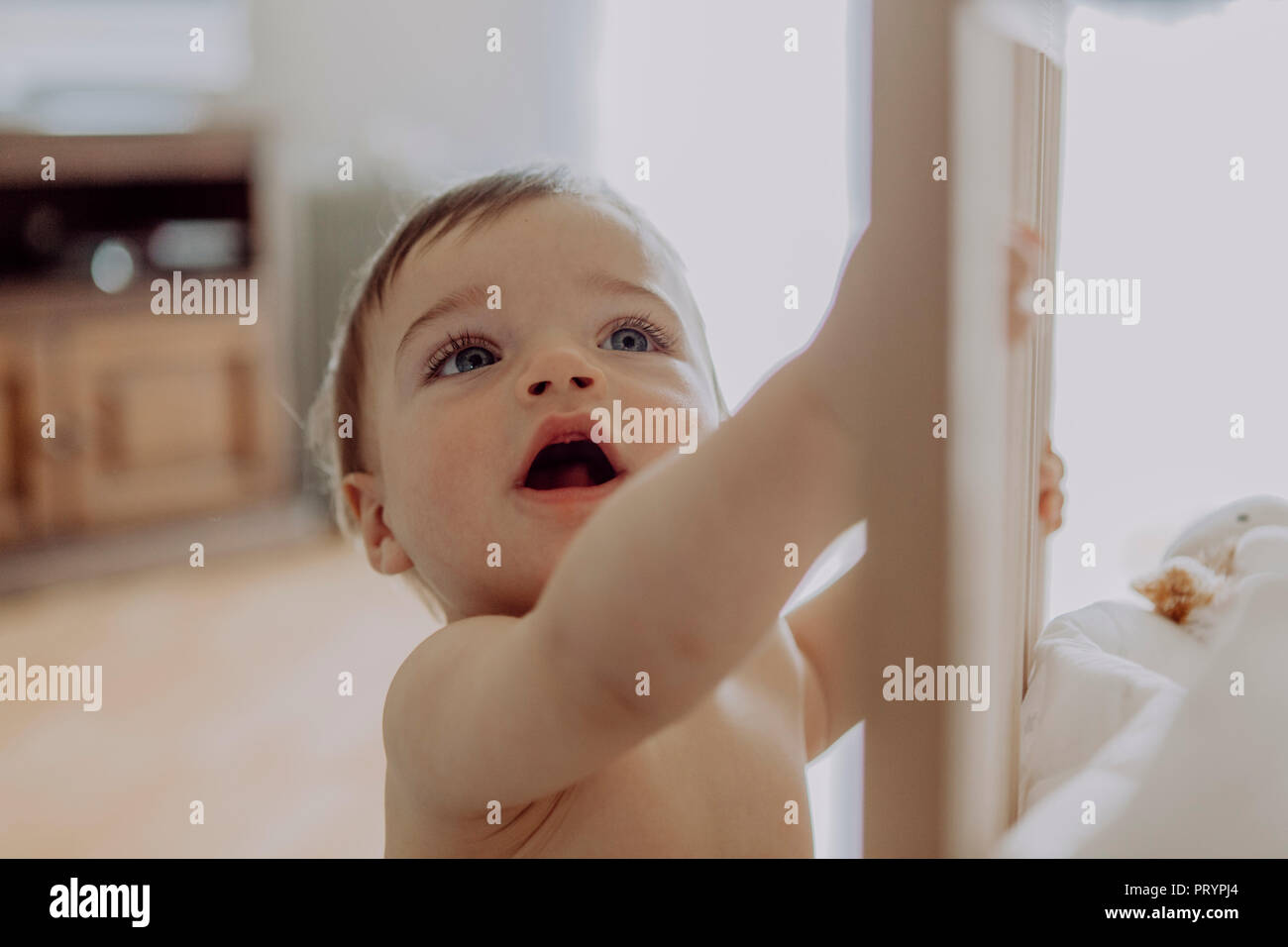 Little boy holding on to his crib Stock Photo Alamy